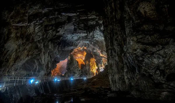 Ziyaretçiler Grutas de Cacahuamilpa Ulusal Parkı 'nda görkemli kaya oluşumlarından büyülenmiş bir patikadan geçiyorlar. Doğal mağara sistemi, çevrenin güzelliğini artıran mavi ışıklarla aydınlatılan eşsiz jeolojik özellikler sergiliyor.