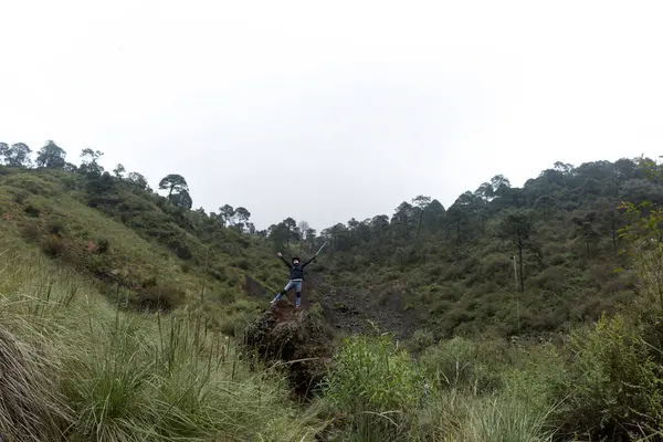 Yürüyüşçüler, yemyeşil yemyeşil ve dramatik kaya oluşumlarıyla çevrili Mexico City 'deki Volkan Ajusco' nun engebeli arazisinde geziniyorlar. Bulutlu gökyüzü maceraya karamsar bir atmosfer ekliyor, grup nefes kesen manzaraları izlemek için duruyor..