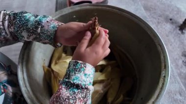 Yerel mutfak ortamında mısır kabukları ve ellerle geleneksel yemek hazırlıyorum.