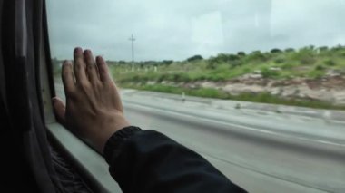 Manzaralı manzaralarda seyahat ederken bir otobüs camından uzanan el.