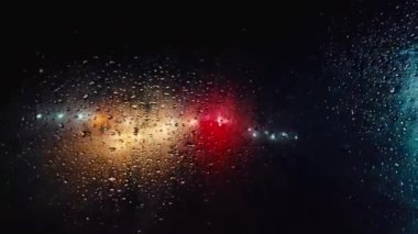 Renkli ışıklar ve yağmur damlaları canlı bir gece atmosferi yaratır.