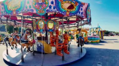 Canlı bir eğlence parkında neşeli bir şekilde dönen renkli bir atlıkarınca.