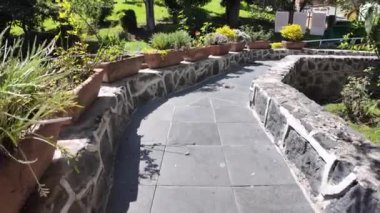 Taş kenarlı manzaralı bahçe yolu ve dingin bir ortamda canlı yeşillik.