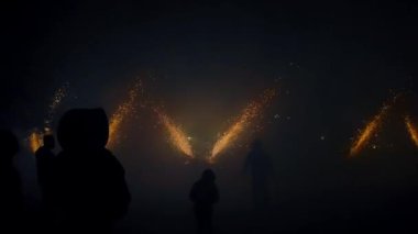 Renkli ışık görüntüsü, parlak kıvılcımlar ve gölgelerle gece gökyüzünü aydınlatır.