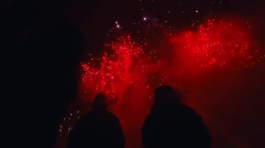 İnsanlar, karanlık bir arkaplan karşısında renkli ışıkların canlı gösteriminin keyfini çıkarıyorlar.