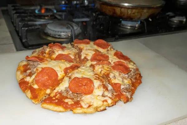Ev yapımı pepperoni ve biftekli pizza mutfakta hazırlanıyor.
