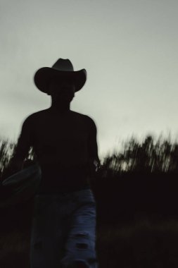 Vaquero Mexicano, Meksika 'nın kırsal kesimlerinde, ormanlık bir bölgede gün batımında yürüyor.