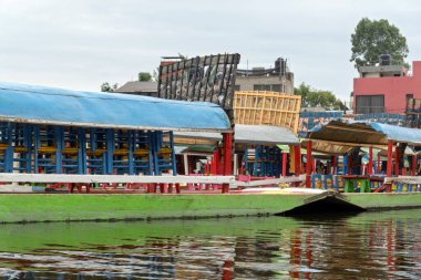 Meksika Xochimilco kanallarında dizilmiş renkli trajineralar bulutlu bir gökyüzünün ortasında