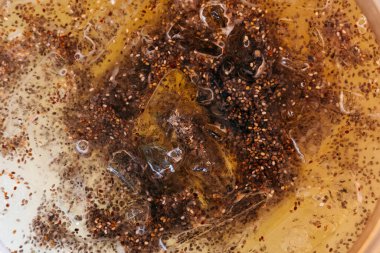 Parlak, ferahlatıcı chia suyu lezzetli limonla doldurulur ve buzla soğutulur. Karışım, açık bir sıvı içinde asılı olan chia tohumlarının ayırt edici dokusunu gösteriyor..