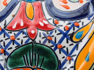 Yetenekli bir zanaatkar titizlikle Meksika 'da Talavera çömleği yaratıyor, canlı renkler ve karmaşık desenler sergiliyor. Masa çeşitli seramik parçalarla süslenmiş. Geleneksel işçiliğin vurgulanması için..