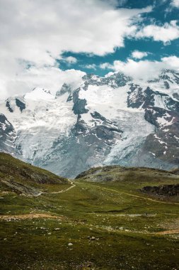Path among snow mountains. Zermatt, Swiss Alps. Adventure, hiking in Switzerland, Europe. Place for loneliness, silence and relax. Green grass and stones.