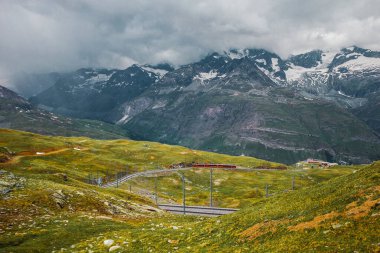 Railway and train in cloudy Gornergrat mountains. Zermatt, Swiss Alps. Adventure in Switzerland. High quality photo