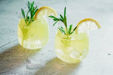 Soğuk kokteyl, limon dilimli limonata, beyaz beton arka planda biberiye bitkisi. Fotoğraf iç. Yüksek kalite fotoğraf