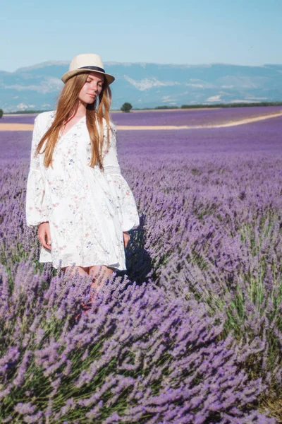 stock image Young woman in hat and dress among lavender fields in Provence, France. Purple flowers lines. Countryside rural summer landscape, Europe. Travel photography.