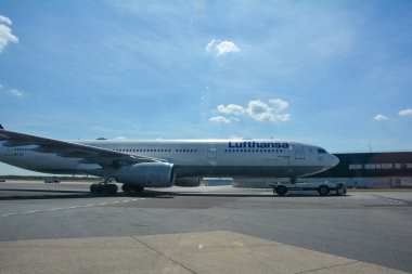 Frankfurt Havaalanı Almanya 2 Ağustos 2022 - Lufthansa makinesi mavi gökyüzü olan bir araç tarafından piste çekildi