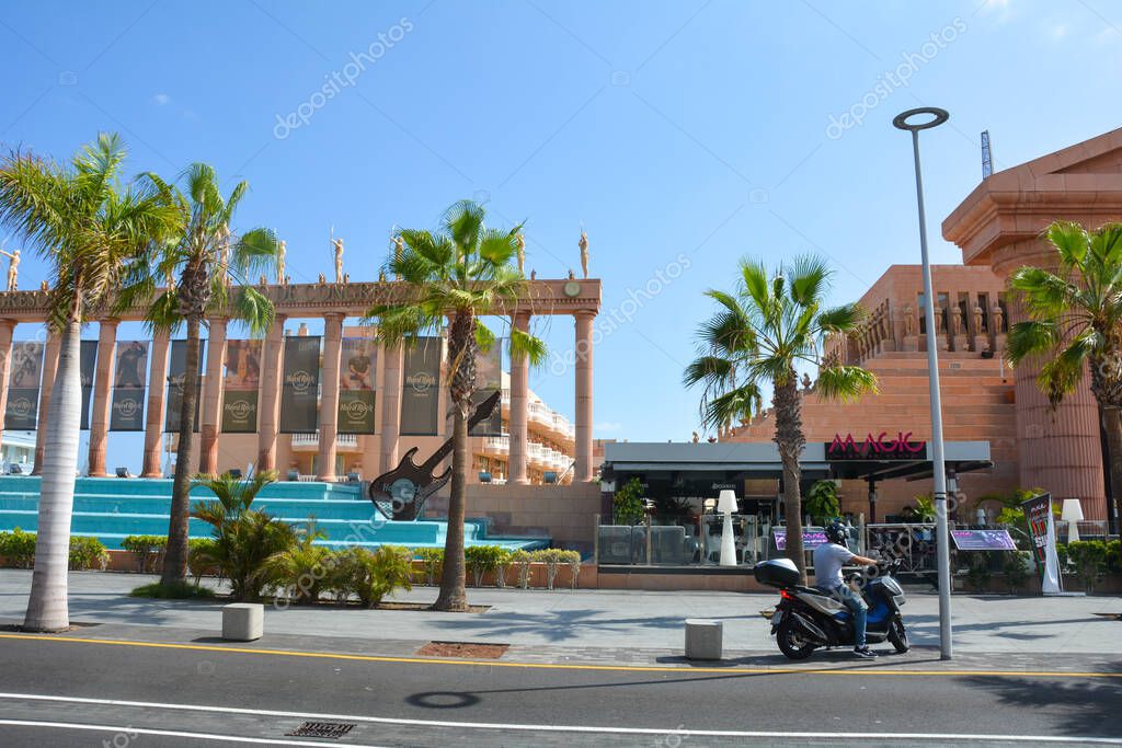 Hard Rock Café, Playa de la Americas, Tenerife, España agosto 12, 2022 -  Vista desde el otro lado de la calle del edificio Café con una motocicleta  y palmeras y cielo azul 2023