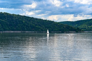 View of the Edersee lake from the dam wall, with boats and sailing ships, with blue sky and clouds, in Hesse, Germany