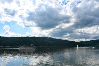 View of the Edersee lake from the dam wall, with a large excursion boat and with blue sky and clouds, in Hesse, Germany