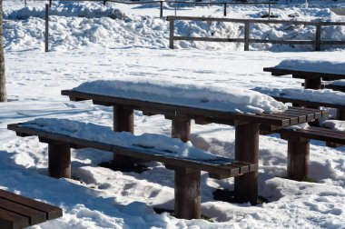 Park bench and table with lots of snow on a cold winter day
