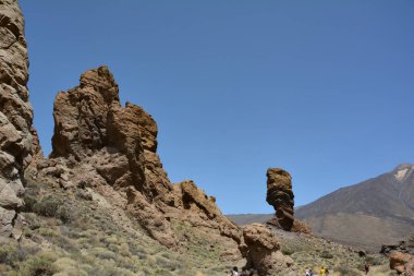İspanya 'nın Tenerife Kanarya Adası' ndaki Teide Ulusal Parkı 'nda volkanik kayadan oluşan tuhaf şekilli Roque Cinchado kayası. Teide Dağı ve mavi gökyüzü manzaralı.