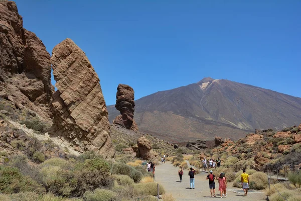 Teide Ulusal Parkı, Tenerife, İspanya 13 Ağustos 2022 - İspanya 'nın Kanarya adası Tenerife' deki Teide Ulusal Parkı 'nda volkanik kayaların tuhaf şekilli Roque Cinchado kayası. Teide Dağı ve mavi gökyüzü manzaralı