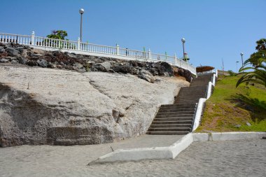 Kosta Adeje, Tenerife, İspanya 'da palmiye ağaçları ve mavi gökyüzü bulunan Torviscas Playa kumsalına merdivenler