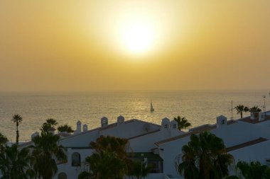 Gün batımında yelkenli teknesiyle denize açılan bungalov kompleksini görün, Costa Adeje, İspanya, Tenerife