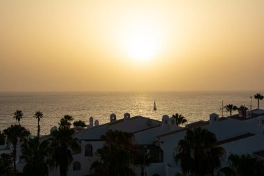 Gün batımında yelkenli teknesiyle denize açılan bungalov kompleksini görün, Costa Adeje, İspanya, Tenerife