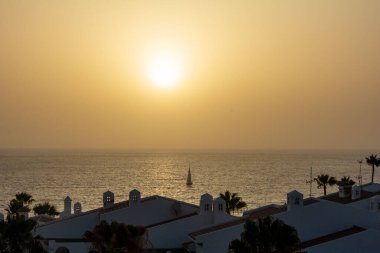 Gün batımında yelkenli teknesiyle denize açılan bungalov kompleksini görün, Costa Adeje, İspanya, Tenerife