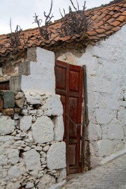 Kapısı olan eski bir ev, asma kilit. Çatı kiremitlerinden bitkiler yetişir.