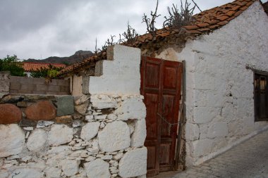 Kapısı olan eski bir ev, asma kilit. Çatı kiremitlerinden bitkiler yetişir.