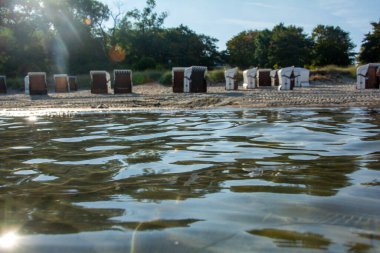 Almanya, Poel 'deki Baltık Denizi' nin suyundan kumlu sahildeki bulanık plaj sandalyelerinin görüntüsü