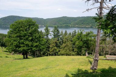 Ağaçlı, mavi gökyüzü ve bulutlu Edersee Gölü manzaralı Hesse, Almanya