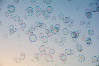 Birçok renkli sabun köpükleri gökyüzünde yüzer.