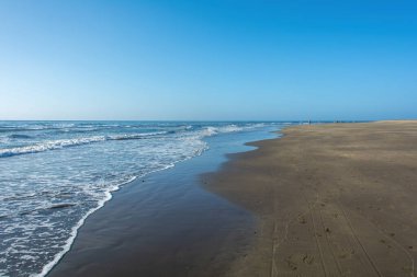 Deniz kenarındaki kumsal Dalgalar ve mavi gökyüzü
