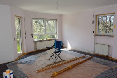 Boya ve yapıştırıcıdan korunmak için zemini bantlanmış bir apartman dairesinde bir oda.