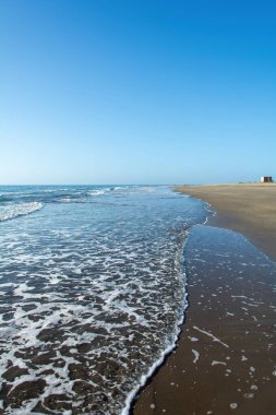 Deniz kenarındaki kumsal Dalgalar ve mavi gökyüzü