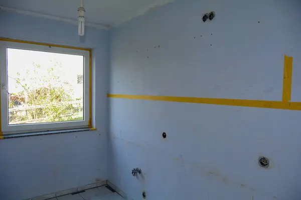 Wall with water and power connections in a kitchen during renovation during a move