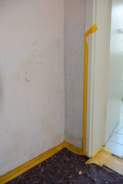 A room in an apartment during renovation with the floor taped off to protect it from paint and paste