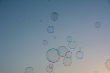 Birçok renkli sabun köpükleri gökyüzünde yüzer.