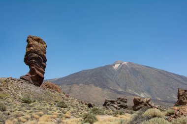 İspanya 'nın Tenerife Kanarya Adası' ndaki Teide Ulusal Parkı 'nda volkanik kayadan oluşan tuhaf şekilli Roque Cinchado kayası. Teide Dağı ve mavi gökyüzü manzaralı.
