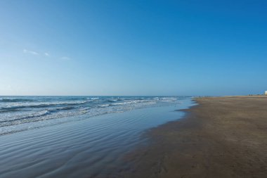 Deniz kenarındaki kumsal Dalgalar ve mavi gökyüzü