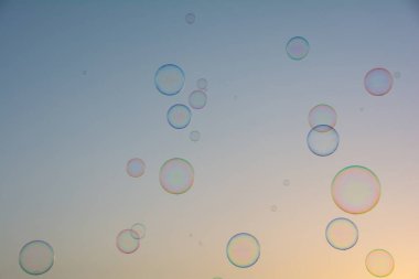 Birçok renkli sabun köpükleri gökyüzünde yüzer.