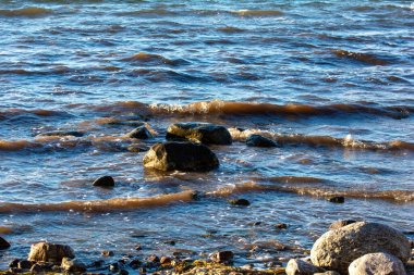 Baltık Denizi kıyısında dalgalı sularda büyük taşlar yatar.