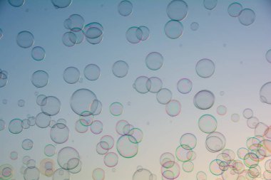 Birçok renkli sabun köpükleri gökyüzünde yüzer.