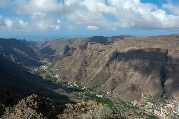 Mountains with a small village in the valley on the Canary Island of Gran Canaria in Spain, with blue sky and clouds