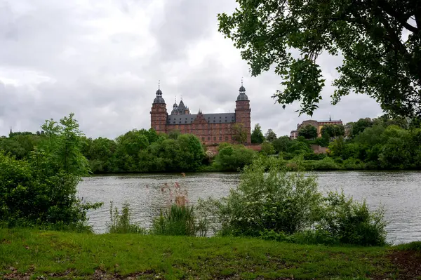 Aschaffenburg, Almanya 'daki şatonun önü ağaç ve nehir manzaralı.