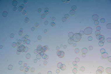 Birçok renkli sabun köpükleri gökyüzünde yüzer.