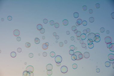 Birçok renkli sabun köpükleri gökyüzünde yüzer.