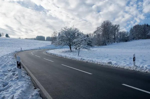 stock image Snow landscape with trees, road and blue sky with clouds